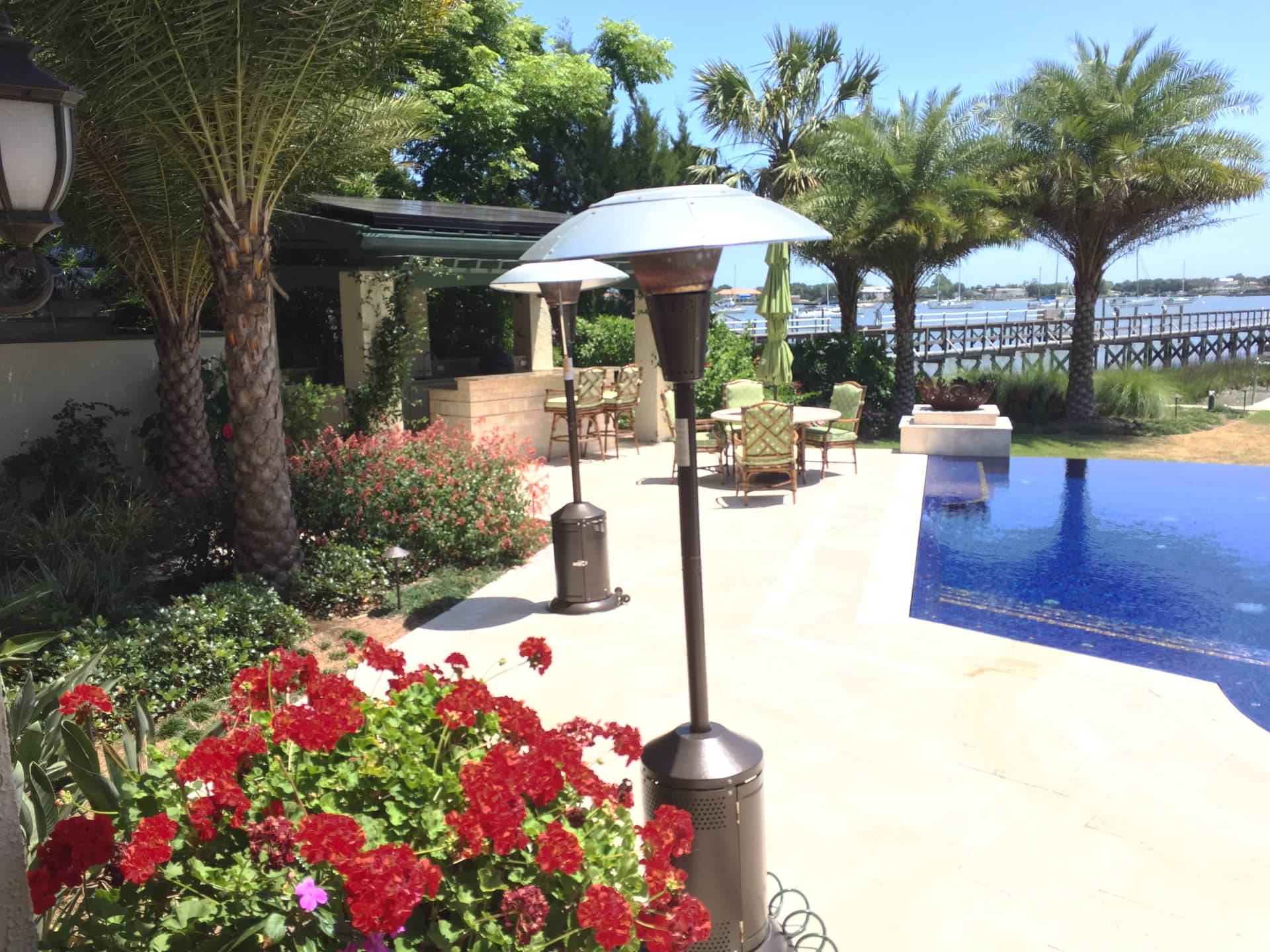 Southern Horticulture landscape installation, waterfront patio with palms, geraniums, and an infinity pool